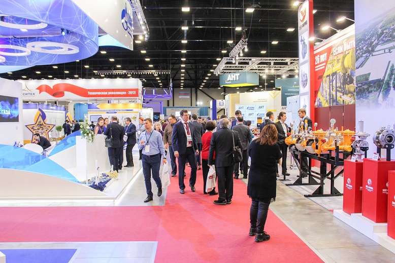 Busy exhibition hall with branded stands, display panels and visitor areas