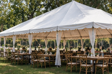An empty outdoor event marquee set up with tables, chairs and lighting