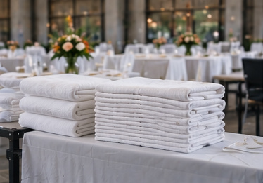 Folded white rental linens on a table in an event space